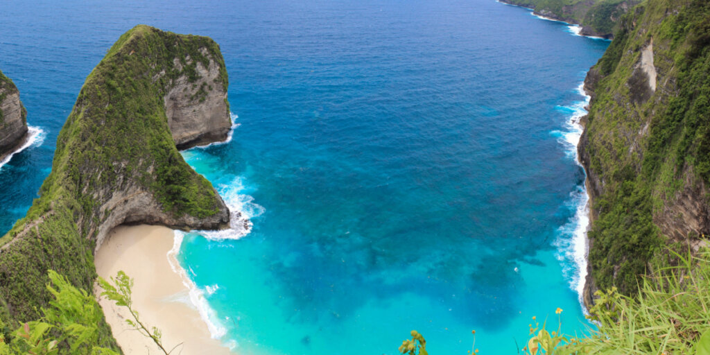 faixa de praia cercados por montanhas e o mar azul 