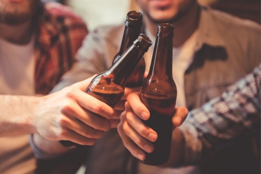 Pessoas brindando com garrafas de cerveja