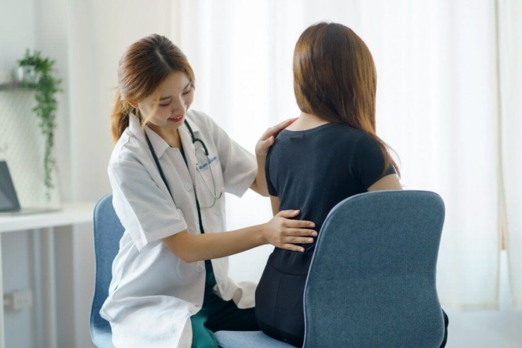 médica examinando costas de mulher sentada de costas