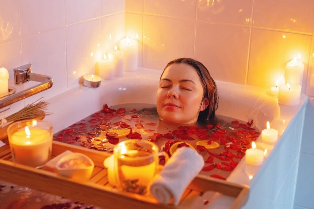 Mulher dentro de uma banheira tomando banho com pétalas de rosas vermelhas 