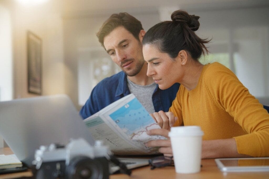 Homem e mulher sentados sem frente a um notebook e olhando um mapa