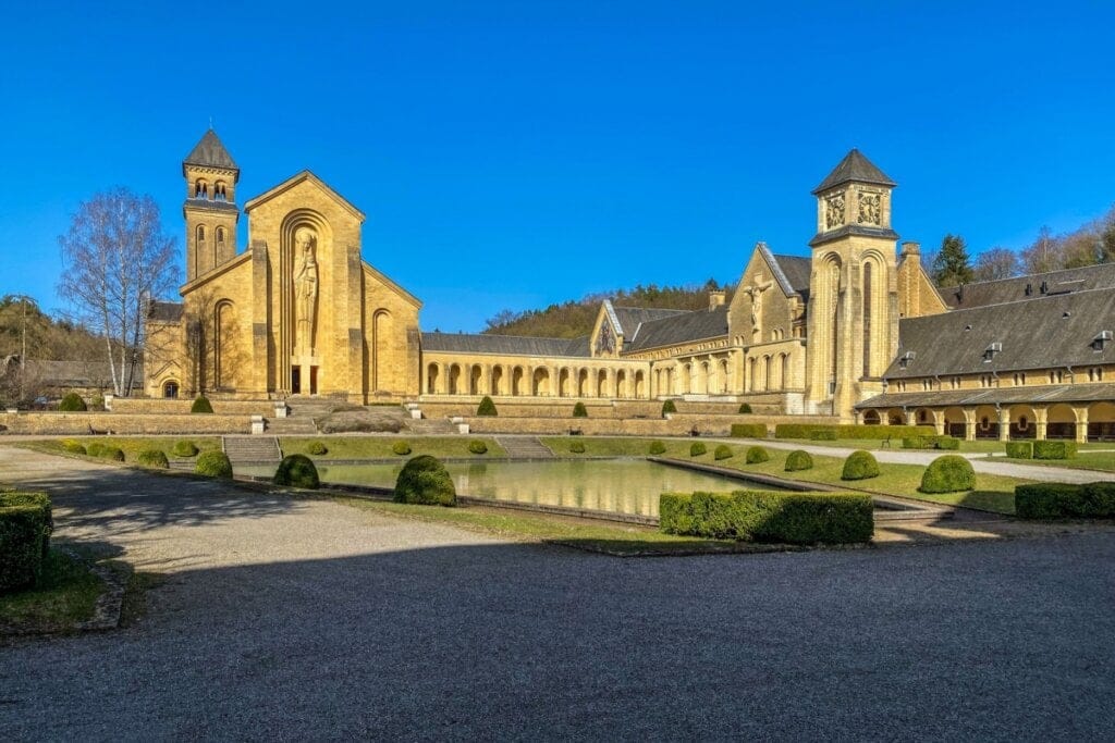 Abadia trapista cisterciense de Orval com céu azul acima dela 