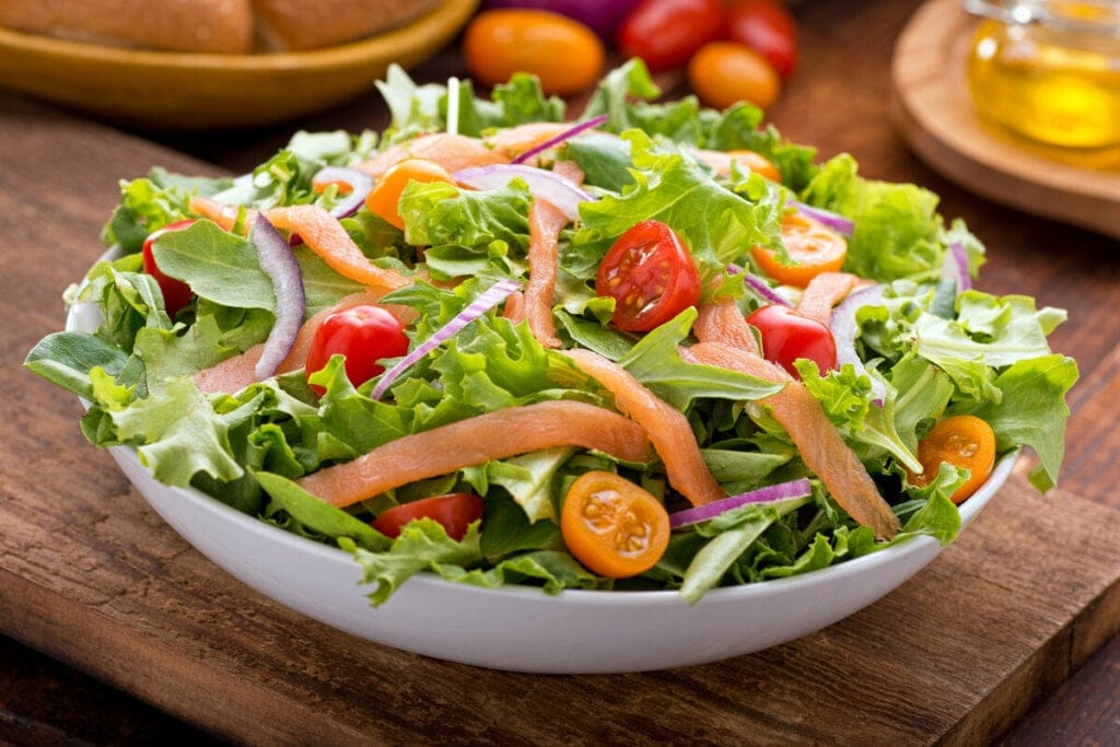 Prato branco com salmão, alface, tomate e cebola-roxa 