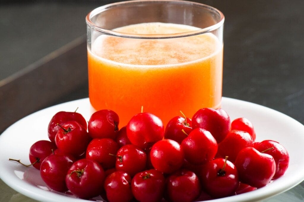 Prato branco com acerolas frescas e suco de acerola 