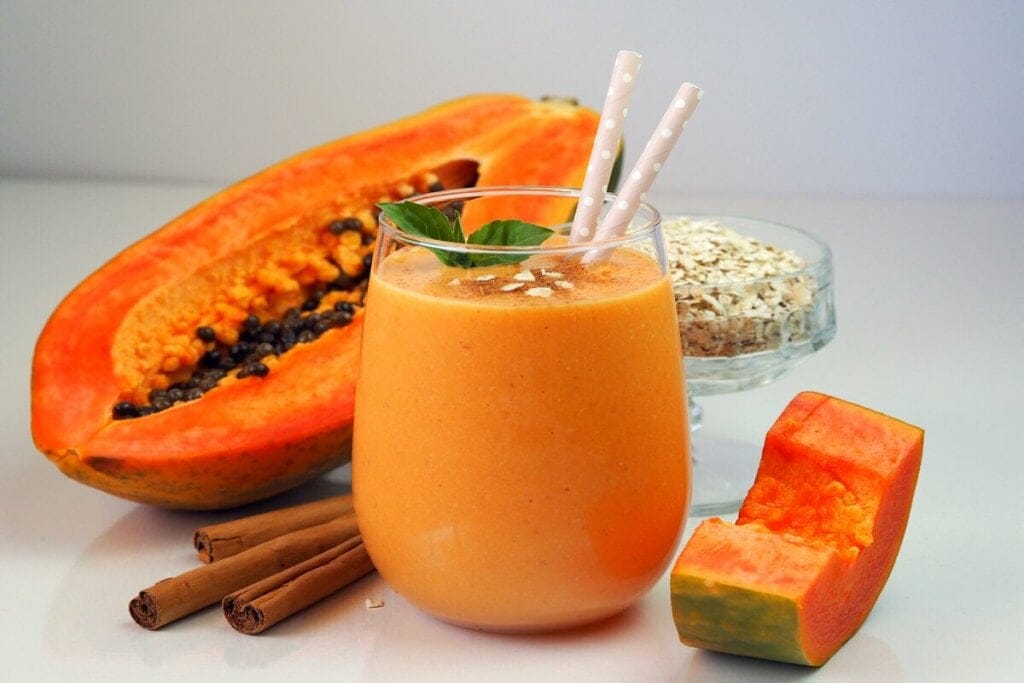 Copo de vidro com vitamina de mamão decorado com flocos de aveia e folhas de hortelã