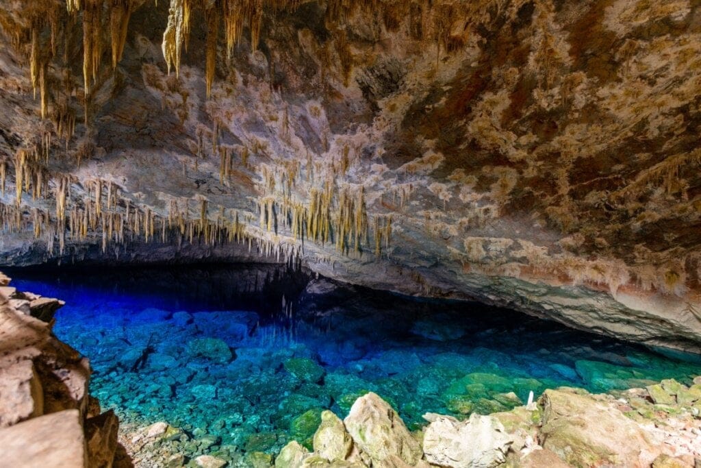Imagem de uma caverna com um lago com água azul e verde