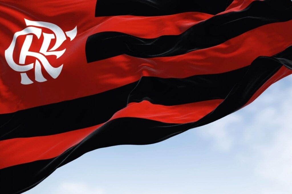 Bandeira do Flamengo voando em frente a um céu-azul com nuvens