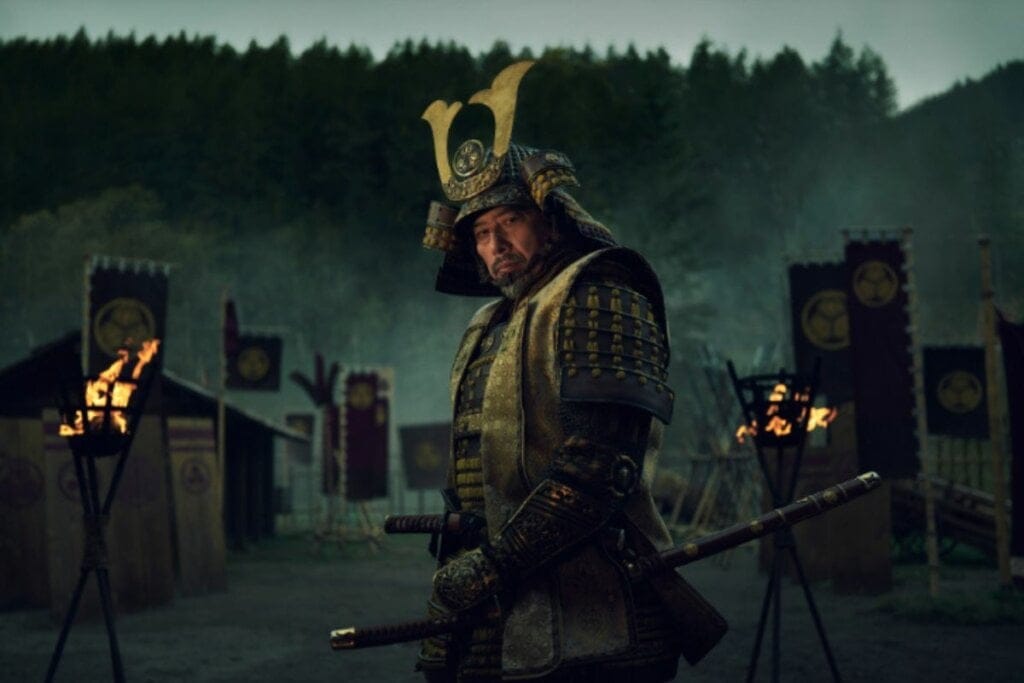 Protagonista da série Xogum vestido com armadura para guerra e segurando uma espada