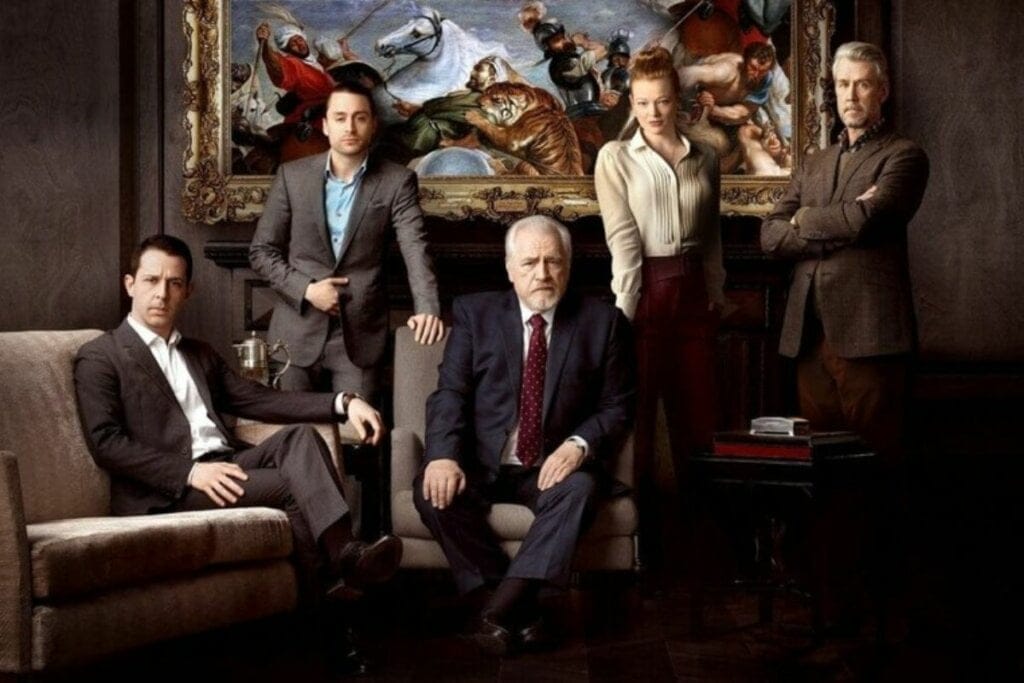 Personagens da série Succession vestidos com roupa social, sentados e em pé em frente a um quadro