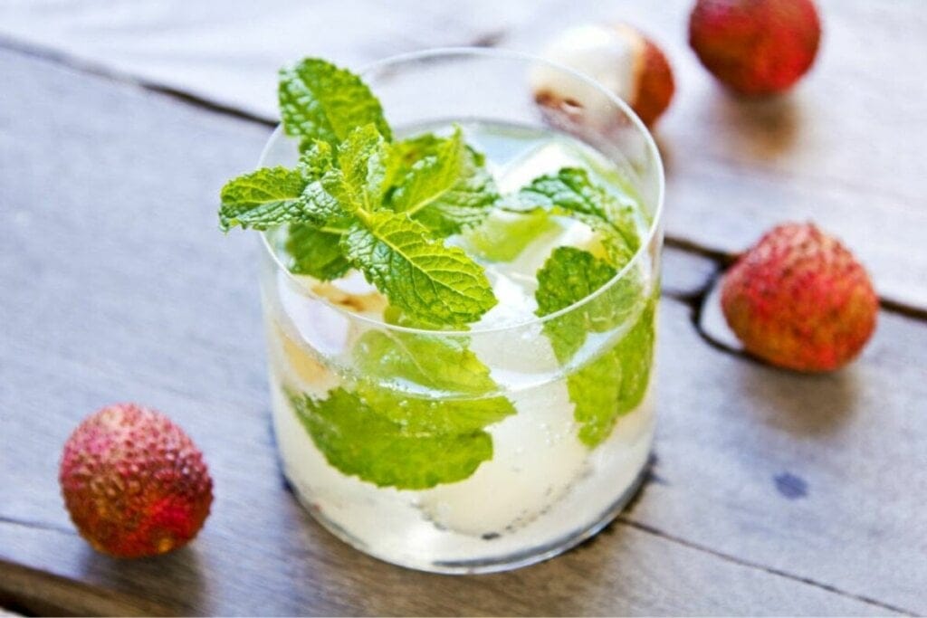 Copo de vidro com suco de lichia decorado com folhas de hortelã