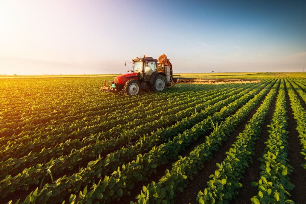 Trator realizando cultivo em área extensa de agricultura.