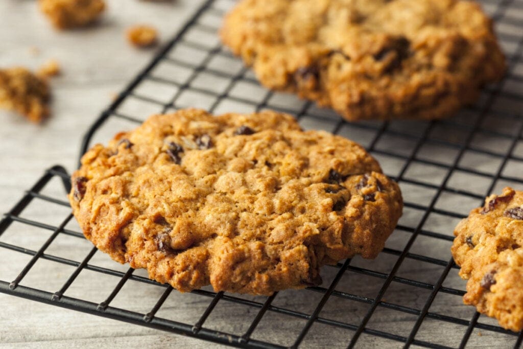 Dois cookies com uvas-passas em cima de uma grade preta