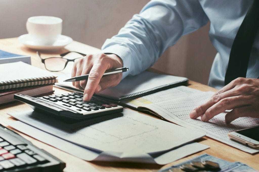Homem realizando contabilidade com calculadora. 