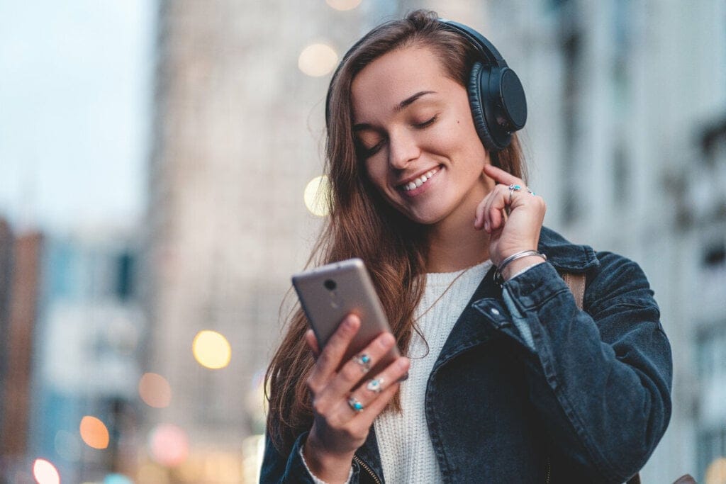 Menina mexendo no celular e usando fone de ouvido na rua