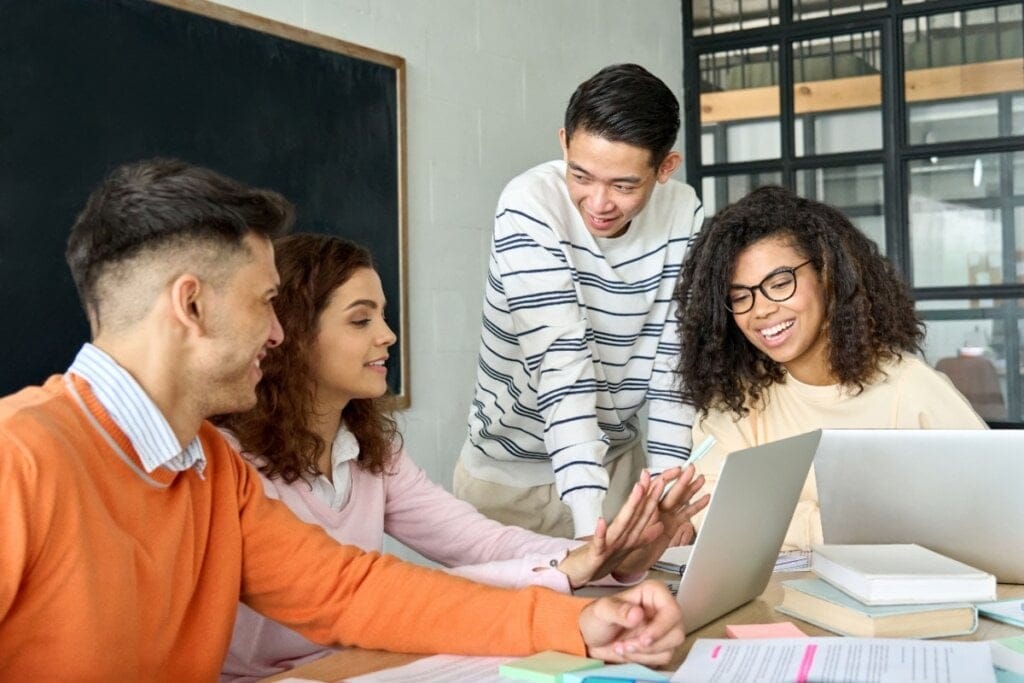 Jovens da Geração Z trabalhando em equipe, interagindo de forma colaborativa em um ambiente com computadores e livros