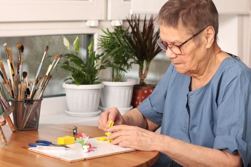 Mulher idosa fazendo escultura com massinha