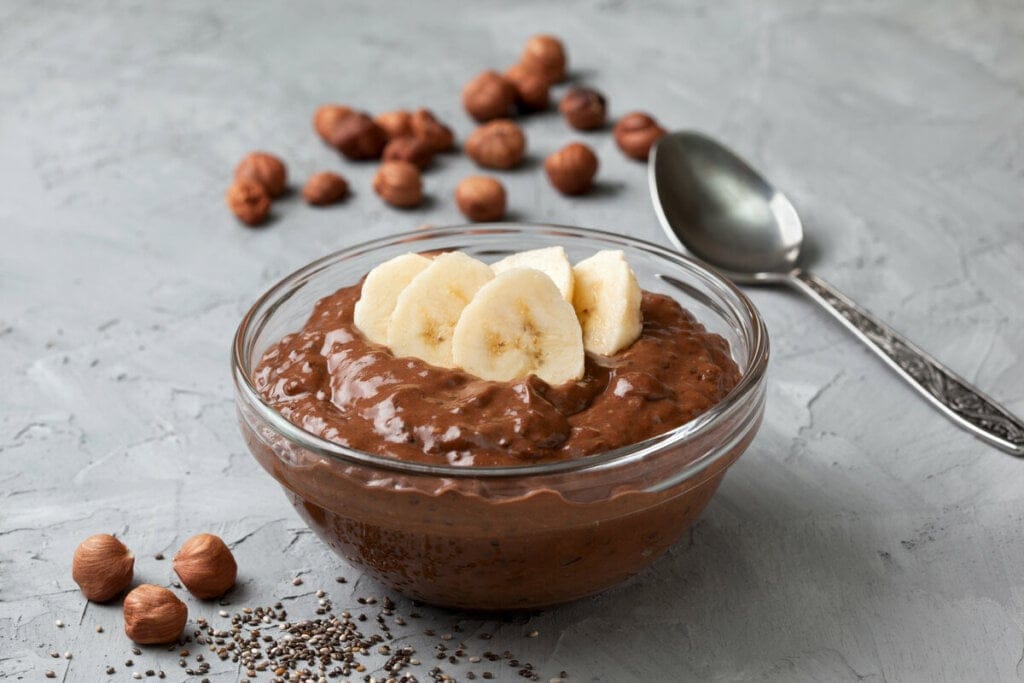 Musse de chocolate com chia em um recipiente branco decorado com pedaços de banana 