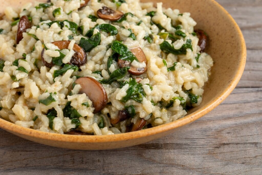 Risoto de cogumelo e espinafre servido em prato fundo de cerâmica 