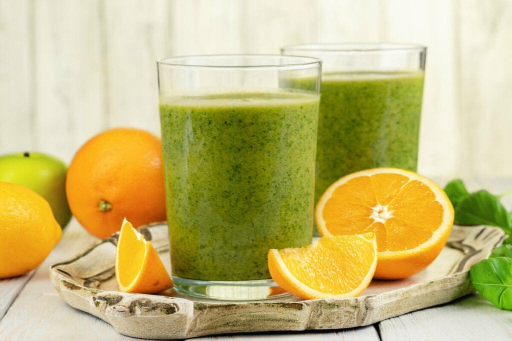 Dois copos de vidro com suco de laranja com couve