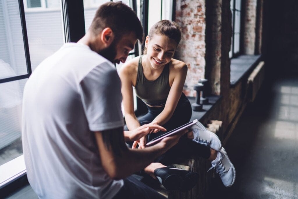Mulher e homem sentados em uma academia conversando 